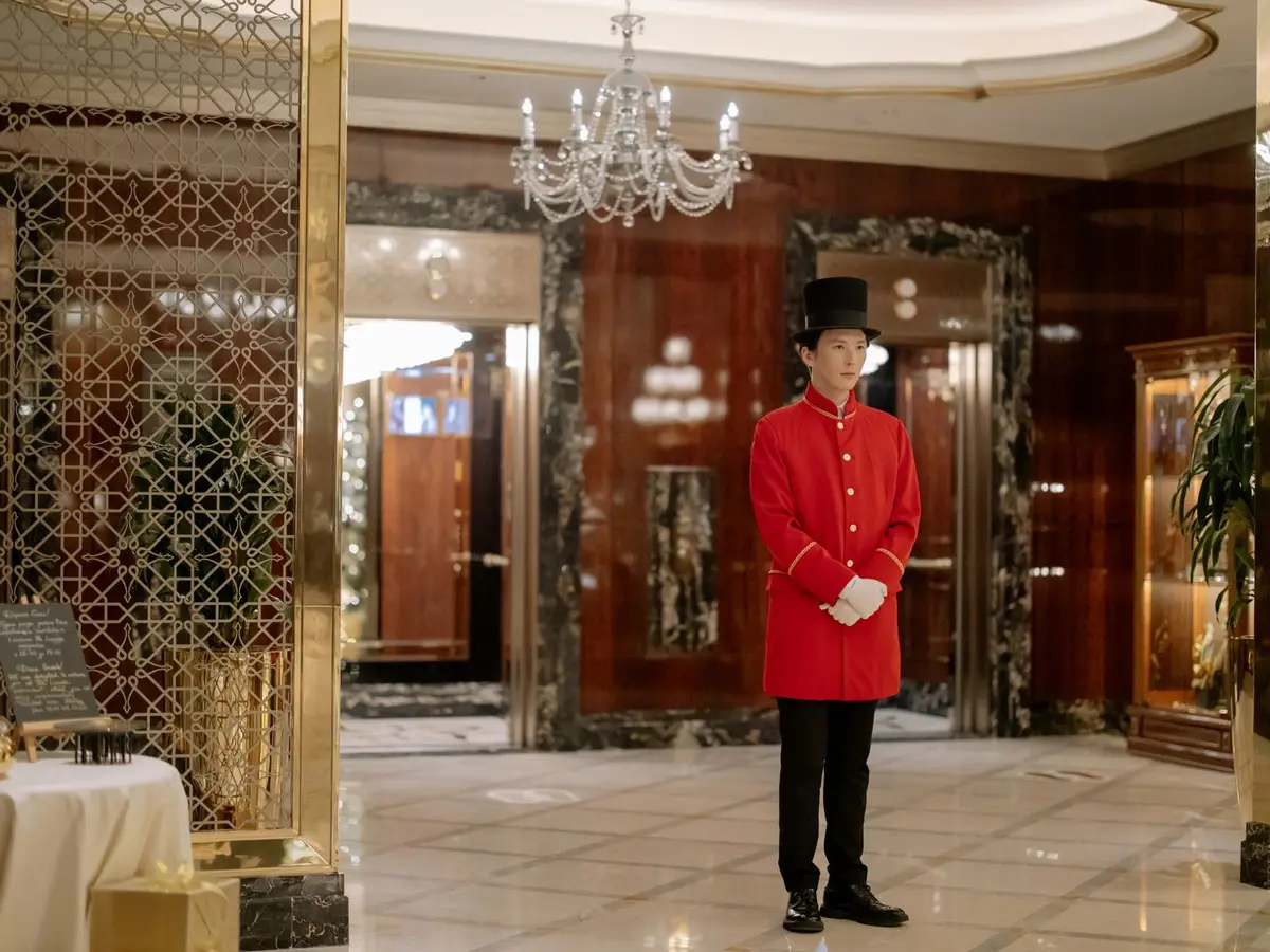A uniformed doorman standing in a hotel lobby